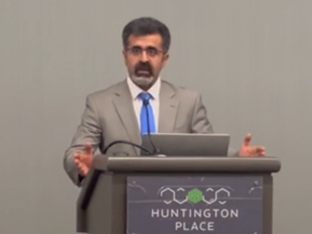 Yousef Khajavigodellou speaking at a lectern at AAG 2025